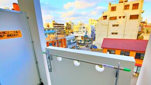 Un balcón con barandilla metálica y vista a un paisaje urbano con diversos edificios.