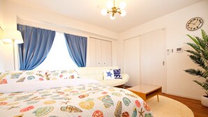 Un dormitorio con cama, sofá, una mesita, un reloj y una planta.