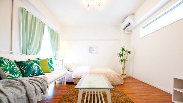 Una sala moderna con una mesa de centro de vidrio, un sofá con cojines estampados, una pequeña mesita auxiliar y una planta en maceta.