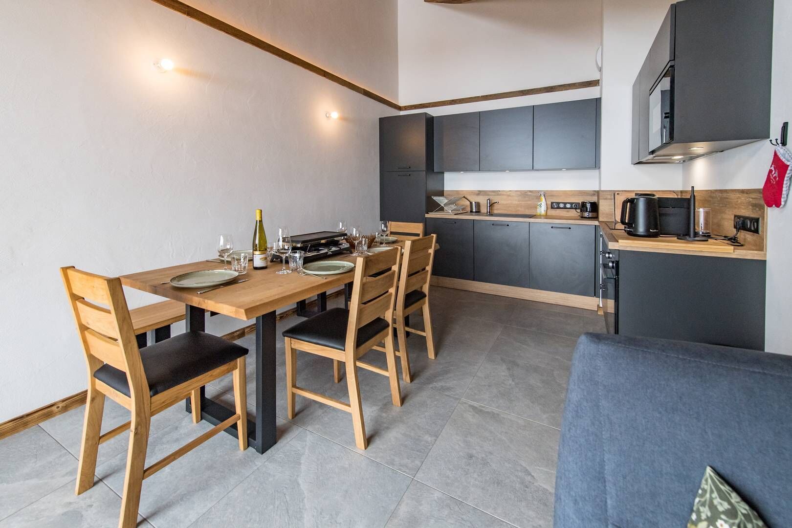 A compact kitchen with dark cabinets, a wooden dining table, and a built-in oven.
