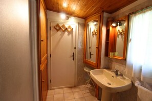 Un baño con puerta de madera, un lavabo y un espejo.