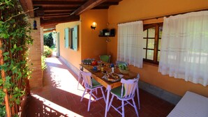 A dining area with a wooden table, chairs, and a window with curtains. - Nice cottage ideal for couples, large enclosed garden with private pool. Pets are welcome. Bucine is (Bucine)
