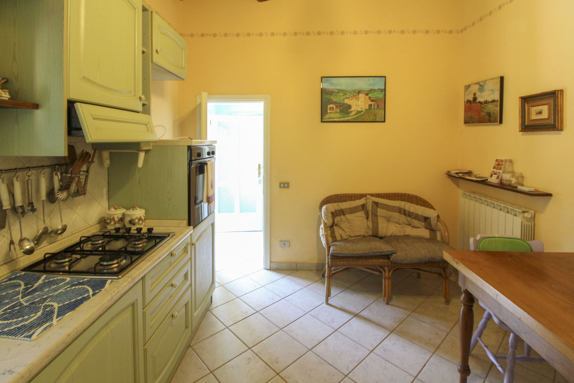 Cuina amb fogó a gas, forn i zona de menjador amb taula i cadira.
