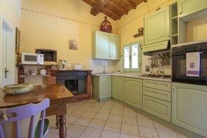 A kitchen with green cabinets, a microwave, a stove, and a fireplace. - Nice cottage ideal for couples, large enclosed garden with private pool. Pets are welcome. Bucine is (Bucine)