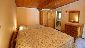 A bedroom with two beds, wooden wardrobe, and a mirror. - Nice cottage ideal for couples, large enclosed garden with private pool. Pets are welcome. Bucine is (Bucine)