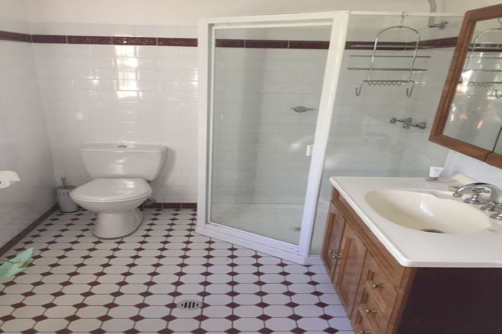 A bathroom with a toilet, a shower enclosure, and a sink with a mirror.