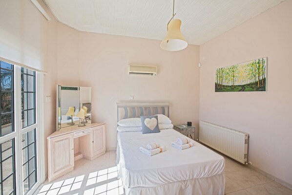 Un dormitorio con cama, mesitas de noche, cómoda, ventana y radiador.