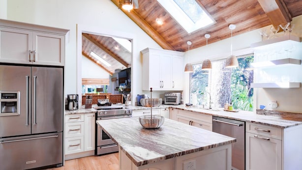 Una cocina moderna con electrodomésticos de acero inoxidable, armarios blancos y una isla grande.