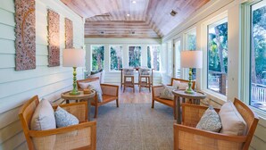 Una habitación acogedora con muebles de mimbre, techo de madera y amplias ventanas que dan a vistas del exterior.