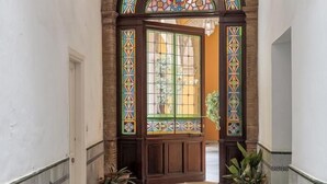 A hallway with a wooden door, stained glass windows, and potted plants. - Dreams of the Cathedral * Oasis in Santa Cruz * (Sevilla)