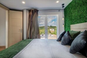 Relax in this serene bedroom with a large bed, sliding glass door to an outdoor area, and a natural touch from the artificial grass wall.