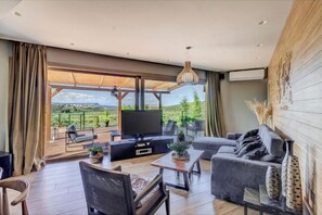 Relax in a stylish living area with a large flat-screen TV, comfortable seating, and a scenic view.