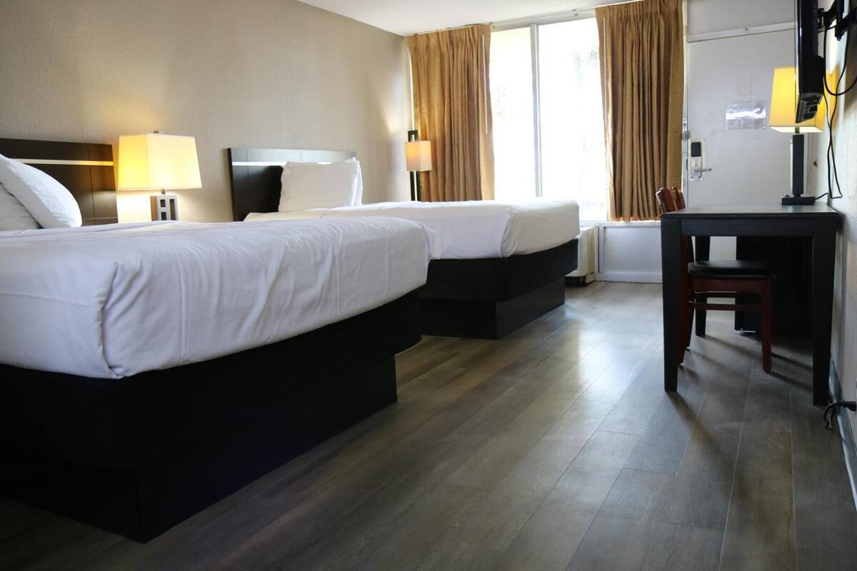 A hotel room with two beds, a desk, and a chair.