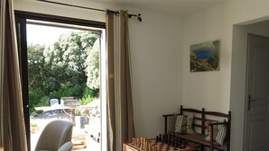 A room with a chessboard, a chair, a sofa, and a door. - Maison récente avec piscine privée à la campagne. (Urtaca)