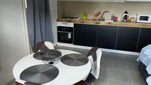 Una cucina compatta con zona pranzo. Dispone di fornelli, microonde, lavello e pensili.