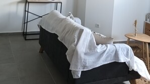 Una camera dal design minimalista con un letto, un piccolo tavolo con uno specchio e un lampadario.