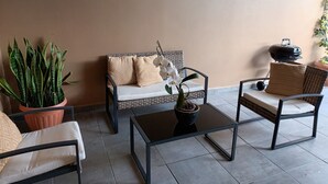 Angolo salotto con divano, due poltrone, tavolino e piante in vaso.