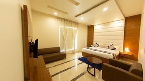 A modern hotel room with a large bed, a sofa, a small table, and a TV. - Comfort Hotel Amritsar (Amritsar)
