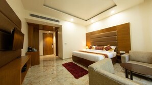 A modern hotel room with a large bed, a TV, a sofa, and a red rug. - Comfort Hotel Amritsar (Amritsar)
