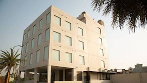A modern building with a flat roof, multiple windows, and a covered entrance area. - Comfort Hotel Amritsar (Amritsar)