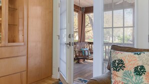 A wooden door leading to a porch with a bench and a view of trees. - Dog Friendly w/ Fenced Backyard - Golf Cart Included - Hot Tub - Fire Pit (Oak Island)