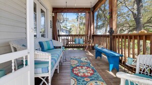 A covered porch with wicker furniture, a colorful rug, and a wooden railing. - Dog Friendly w/ Fenced Backyard - Golf Cart Included - Hot Tub - Fire Pit (Oak Island)