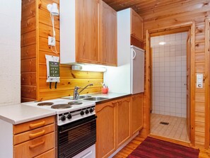 A compact kitchen with wooden cabinets, a stove, and a sink. - Vacation home Ummelo by Interhome (Pelkosenniemi)