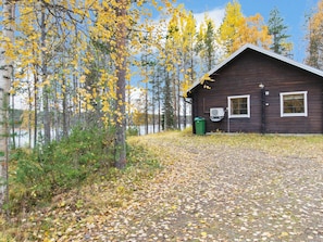 Une cabane offrant une vue dégagée sur un lac, entourée d’arbres aux feuilles jaunes.