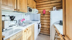 Une cuisine compacte dotée de meubles en bois, d’un four à micro-ondes, d’une machine à café et d’un grille-pain.