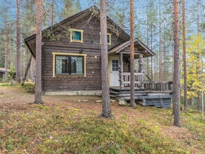 A rustic cabin with a porch, surrounded by a forest. - Munkero by Interhome (Pelkosenniemi)