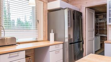 A kitchen with a stainless steel refrigerator, wooden cabinets, a window with blinds, and a countertop with a toaster.