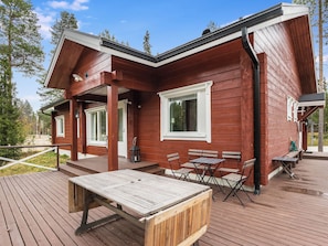A wooden cabin with a deck, outdoor seating, and a covered area.