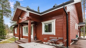 A wooden cabin with a deck, outdoor seating, and a window with shutters. - Isokuru 3 by Interhome (Pelkosenniemi)