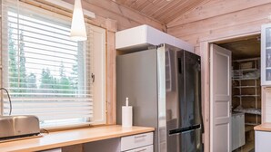 A modern kitchen with a stainless steel refrigerator, wooden cabinets, and a window with blinds. - Isokuru 3 by Interhome (Pelkosenniemi)