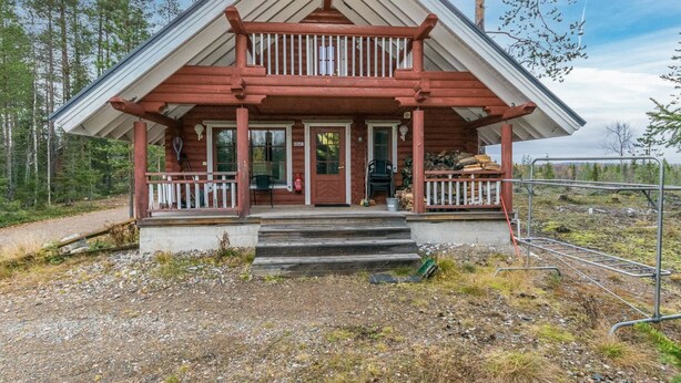 A two-story log cabin with a balcony, a front porch, and a gravel driveway. - Kuukkelin tupa 2 by Interhome (Pelkosenniemi)