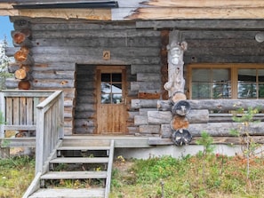 Une cabane en rondins avec une porte en bois, un petit porche et une fenêtre.