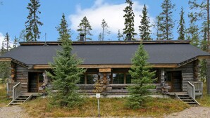 A log cabin with a stone foundation, wooden exterior, and a gravel driveway.