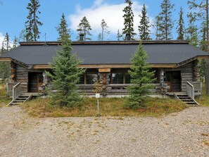 Une cabane en rondins avec des fondations en pierre, un revêtement extérieur en bois et une allée en gravier.