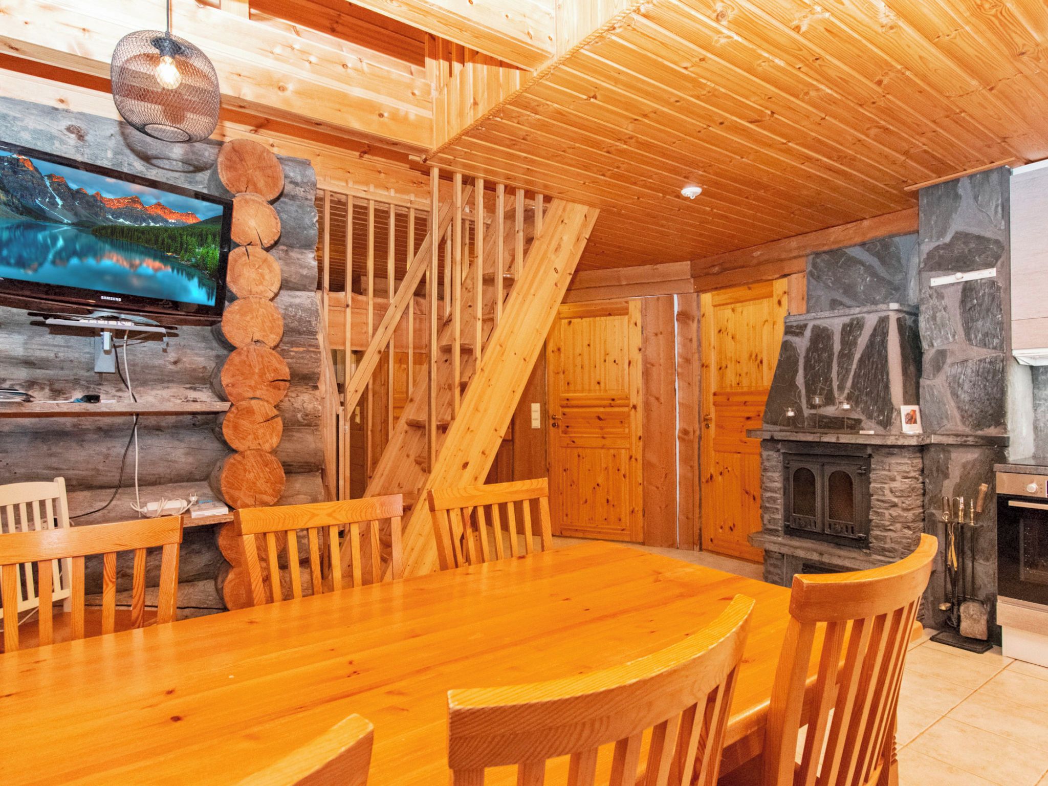 Ein Holzinterieur mit Esstisch, Stühlen, einem Fernseher und einem Kamin.