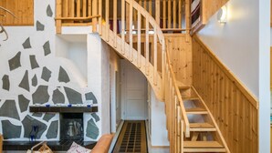 A wooden staircase leading to an upper level, a stone fireplace, and a wooden bench in a modern interior. - Isokurunpuisto a 2 by Interhome (Pelkosenniemi)