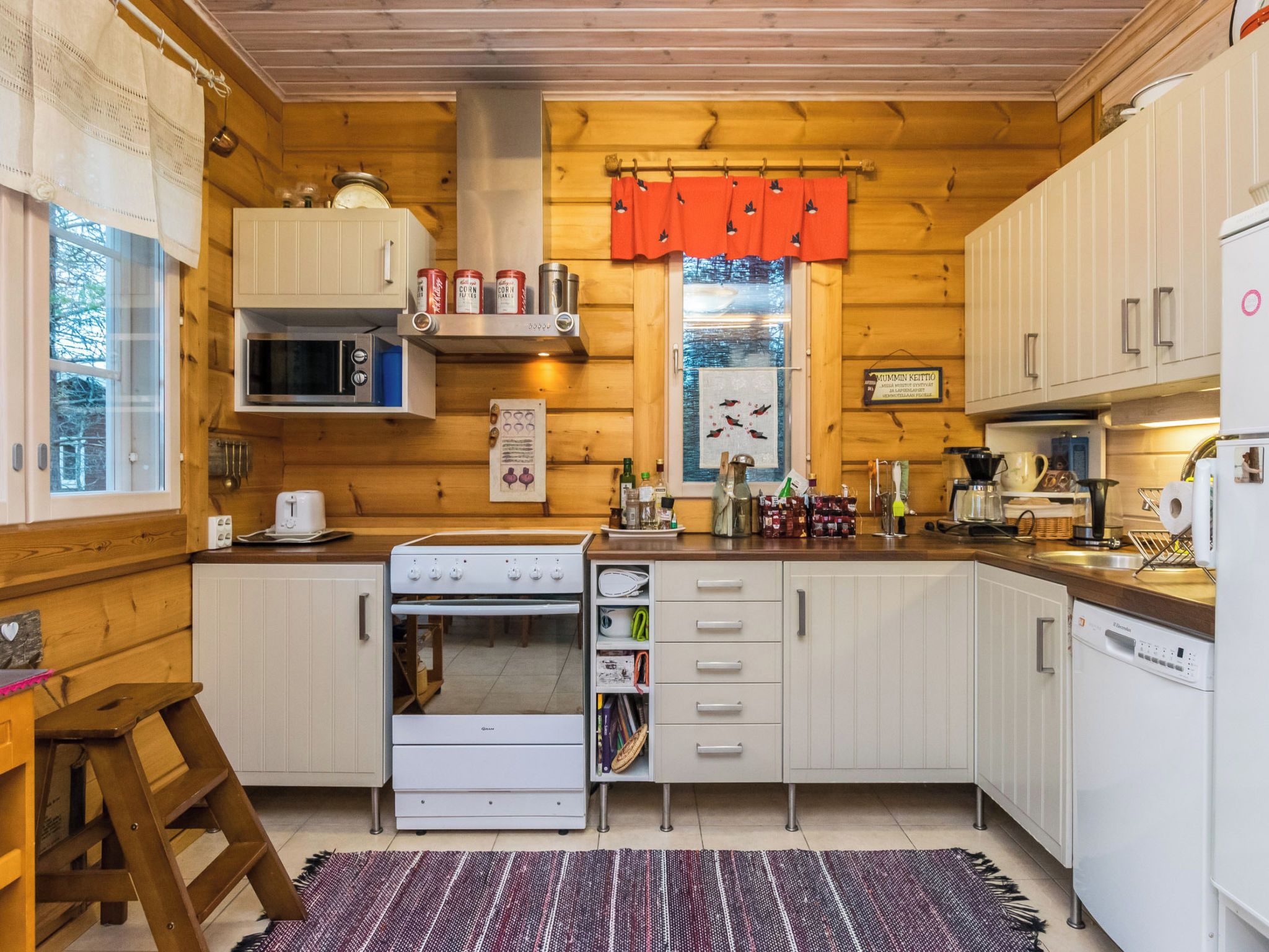 Pieni, käytännöllinen keittiö, jossa on liesi, mikroaaltouuni ja kaapistot.