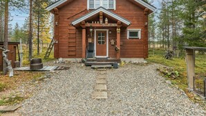 Une cabane en bois avec un porche à l’avant, une porte et une petite fenêtre.