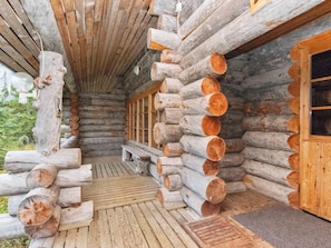 Eine Blockhütte mit einer Holzdiele, großen Fenstern und einer Bank.