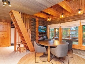 Ein Holzinnenraum mit einem runden Tisch, St ühlen, einem Fernseher und einer Treppe.