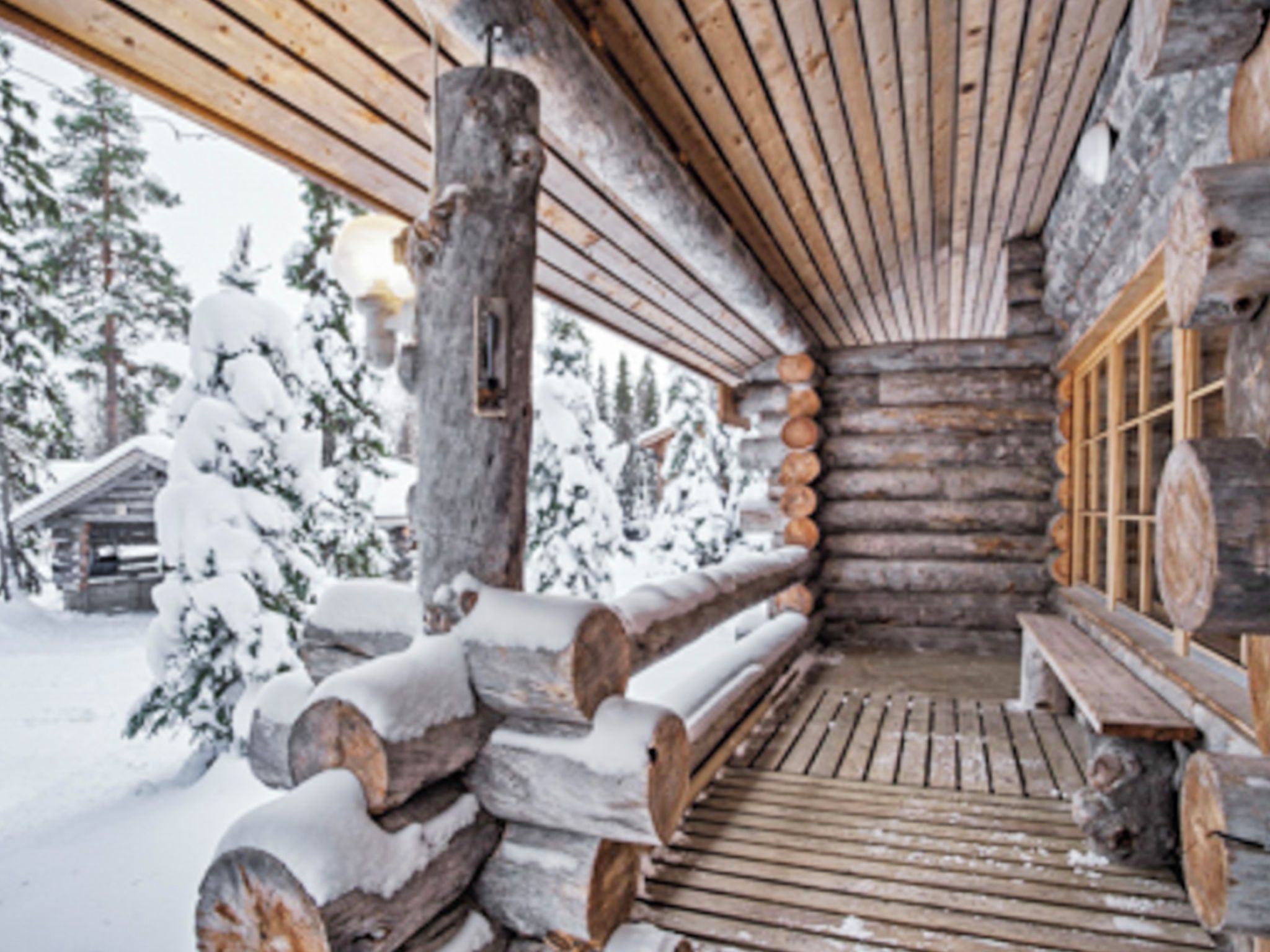 A log cabin with a wooden porch and a snow-covered exterior.