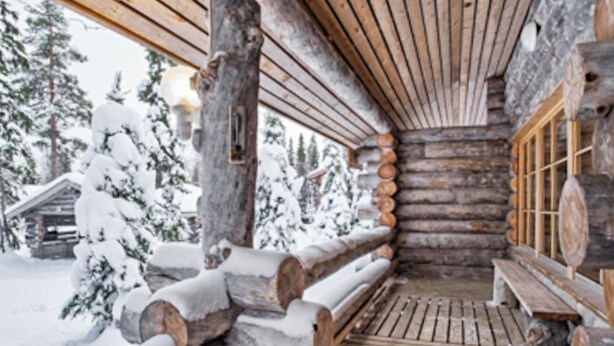 Una cabana de fusta amb una banca de fusta i un paviment de fusta, envoltada d'arbres coberts de neu.