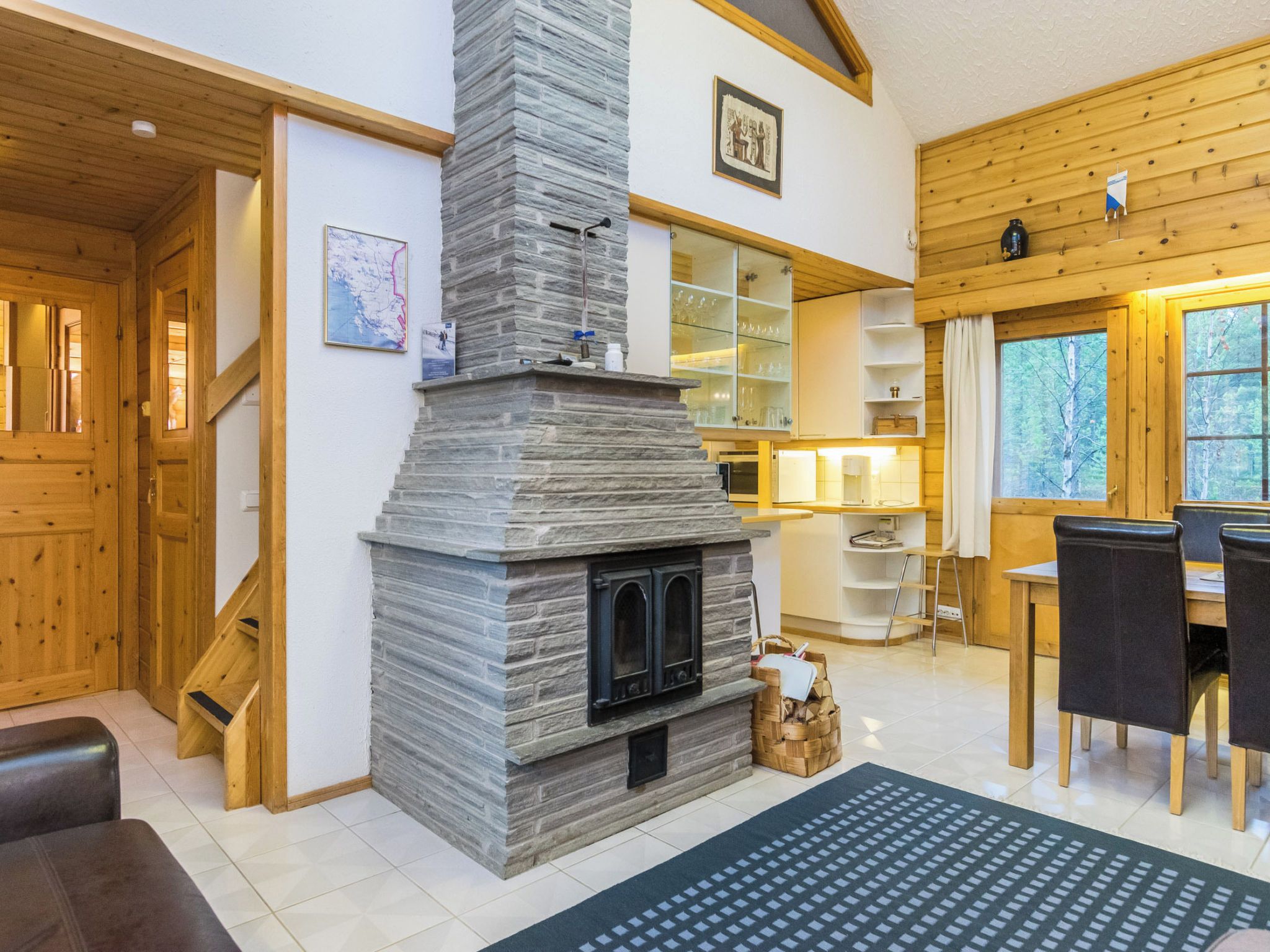 Un intérieur chaleureux avec une cheminée en pierre, des murs en bois, un coin repas et un escalier.