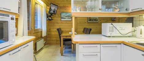 Una cocina compacta equipada con microondas, refrigerador y un armario de vidrio con vajilla.