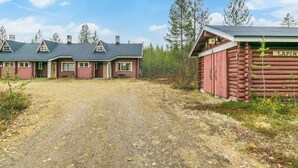 A log cabin with a dirt driveway leading to a row of cabins.