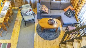 Een knus houten interieur met een bank, een eettafel en een trap.
